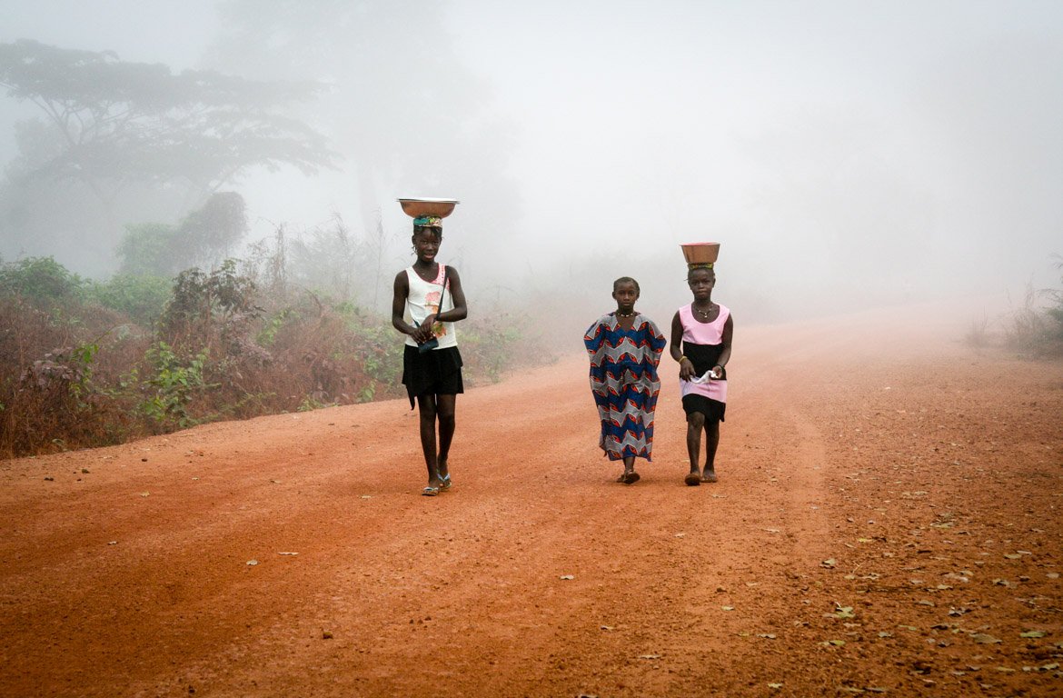 População local a caminhar em estrada de terra batida na Guiné-Bissau.
