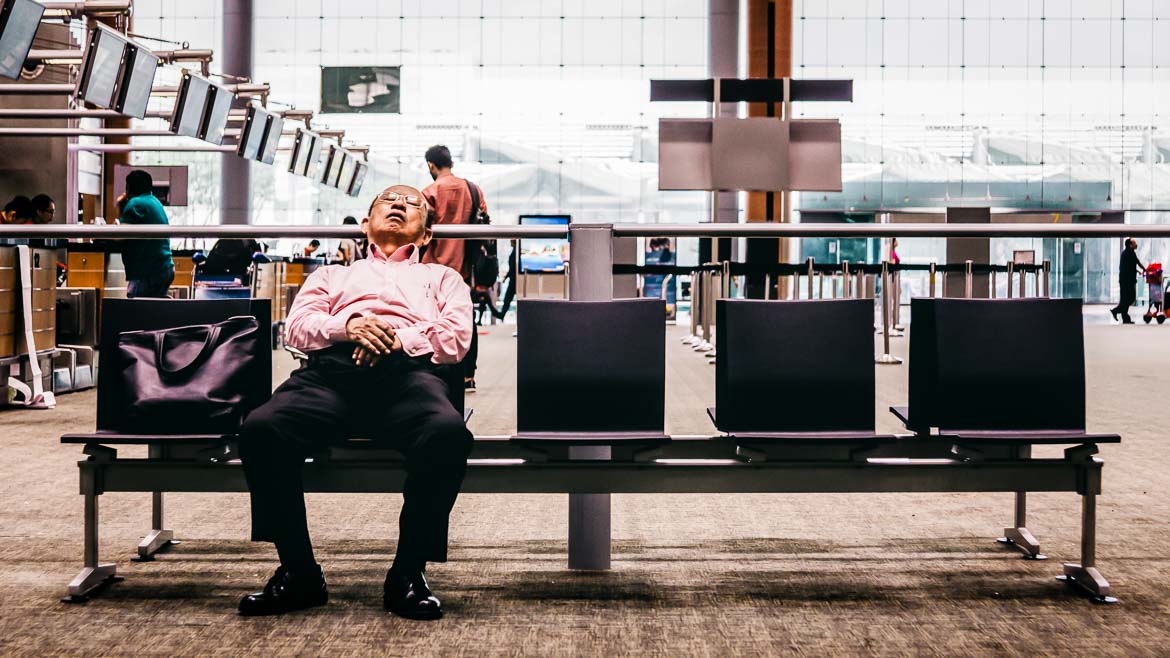 Homem a dormir no aeroporto. Cansaço ou jet lag?