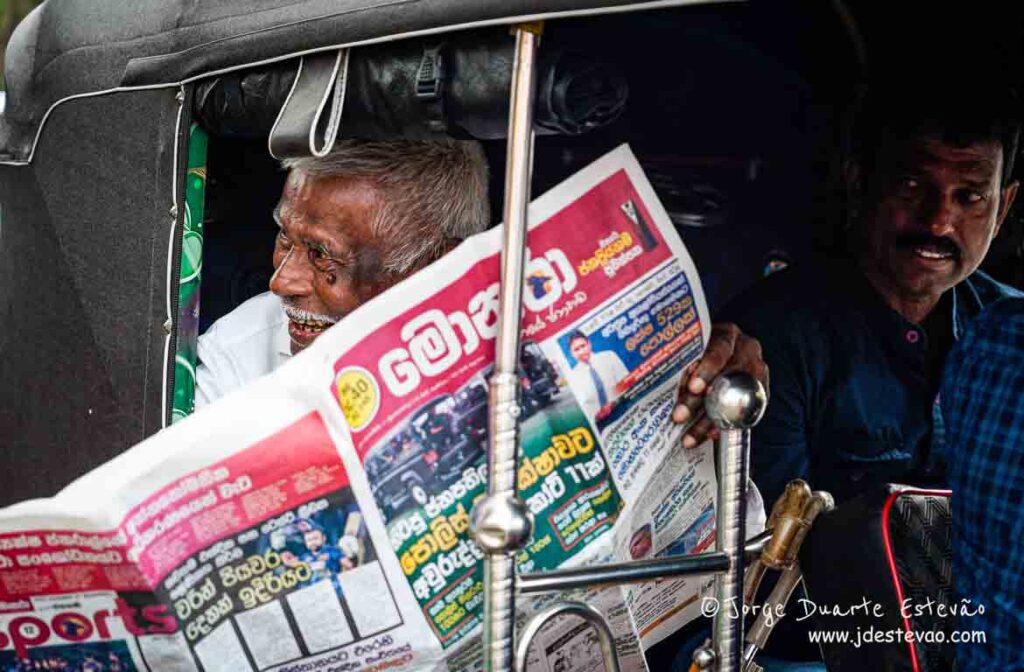 Um homem idoso, imerso na leitura, num tuk-tuk de Galle.