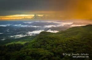 A beleza exuberante da Floresta de Sinharaja, com a luz dourada do pôr-do-sol pintando as nuvens e as montanhas distantes.