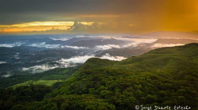 A beleza exuberante da Floresta de Sinharaja, com a luz dourada do pôr-do-sol pintando as nuvens e as montanhas distantes.
