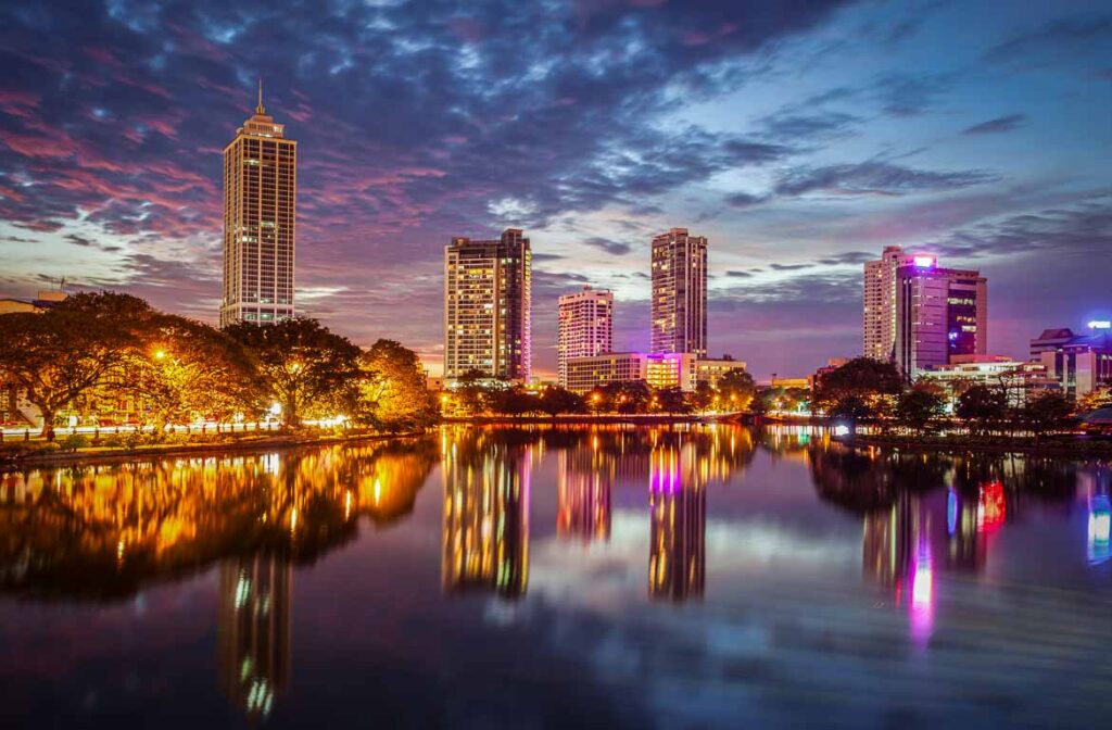 A cidade de Colombo, Sri Lanka, à noite, Lago Beira, com os seus edifícios iluminados a refletir-se no lago, num cenário de beleza nocturna.