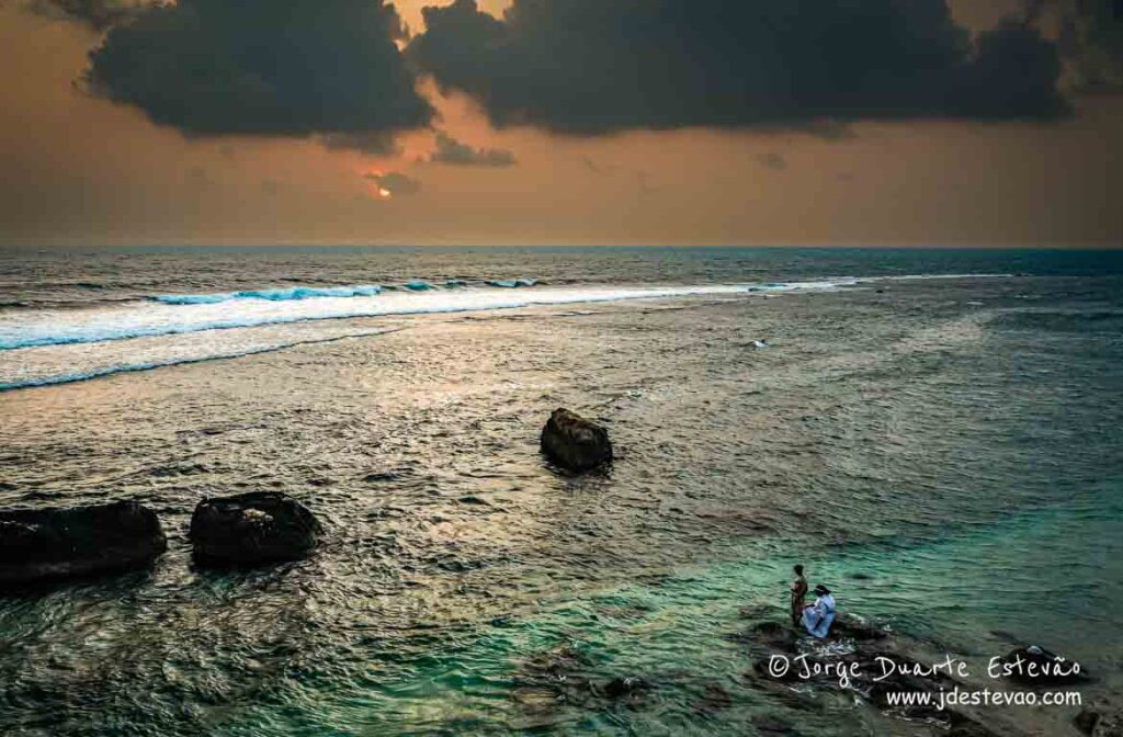 Vista panorâmica da Praia do Faro, Sri Lanka, com um pôr do sol e um mar calmo.