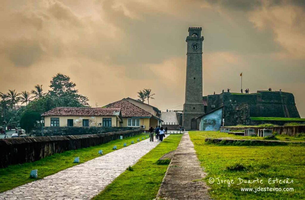 A Torre do Relógio de Galle, Sri Lanka, sob um céu de tons suaves, com pessoas a passear.