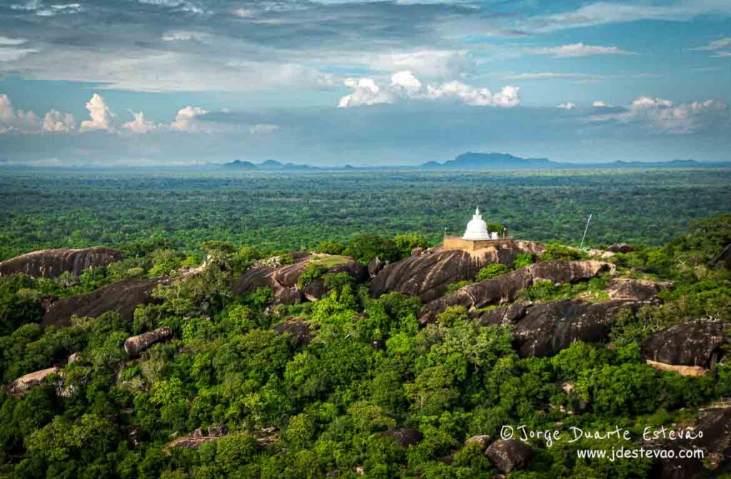 Panorâmica deslumbrante do Parque Nacional Yala, Sri Lanka, com o templo branco de Sithulpawwa em destaque sobre as rochas.