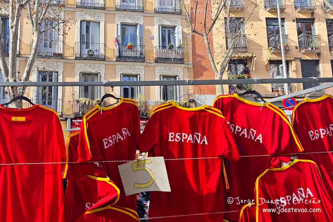 Cores vibrantes das camisolas da Espanha (La Roja) expostas no mercado de rua El Rastro; cultura popular e comércio tradicional no bairro de La Latina, Madrid.