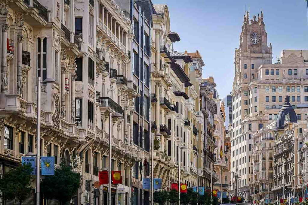 Vista das fachadas ornamentadas da Gran Vía em Madrid, destacando a arquitetura eclética e o icónico edifício da Telefónica ao fundo. A avenida mais famosa para visitar em Madrid.