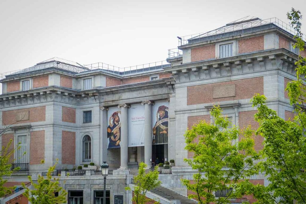 Exterior do Museu do Prado, destacando a arquitetura monumental de Juan de Villanueva e os jardins envolventes. Um ícone do património cultural mundial localizado no Paseo del Prado.